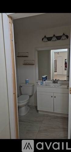 A bathroom with a toilet, sink, and mirror.