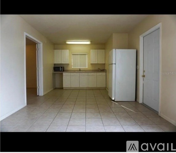 A kitchen with white cabinets and a white refrigerator.