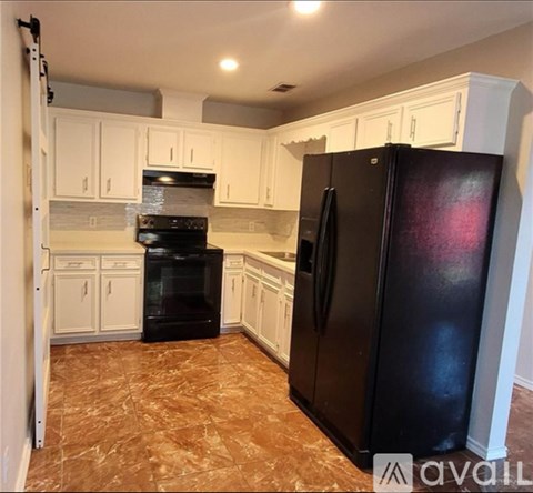 A kitchen with black appliances and white cabinets.