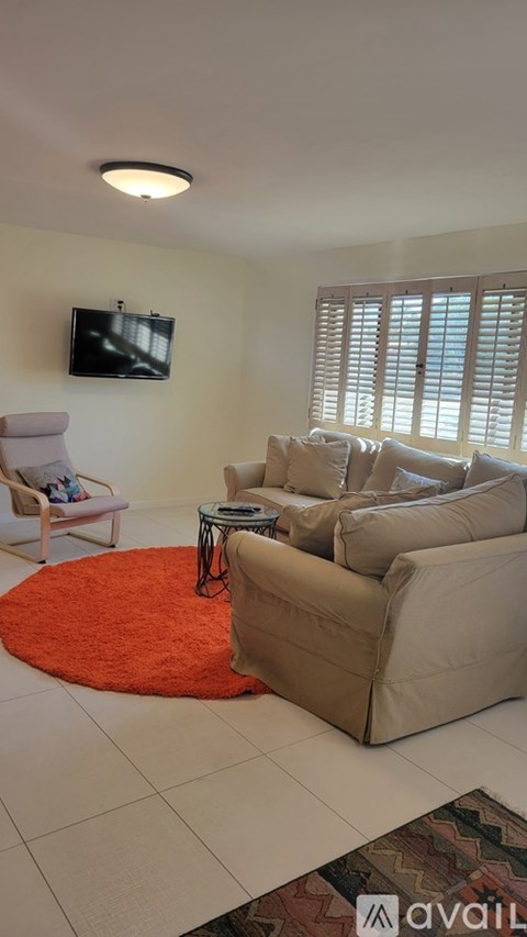 A living room with a white couch and a television on the wall.