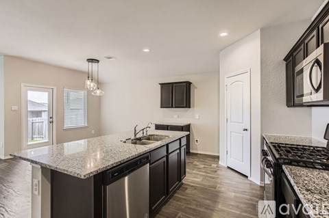 A modern kitchen with dark wood cabinets and granite countertops.