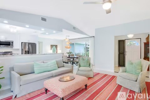A living room with a white couch and a pink ottoman.