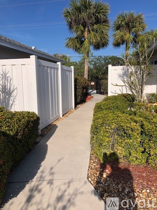 A white fence with a shadow of a person walking on a sidewalk.