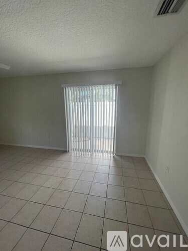 A room with a tiled floor and a window with blinds.