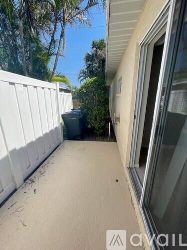 A white fence and a window with a view of trees.