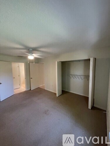 A room with a carpeted floor and a ceiling fan.