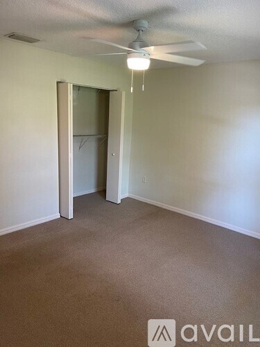 A room with a carpeted floor and a ceiling fan.