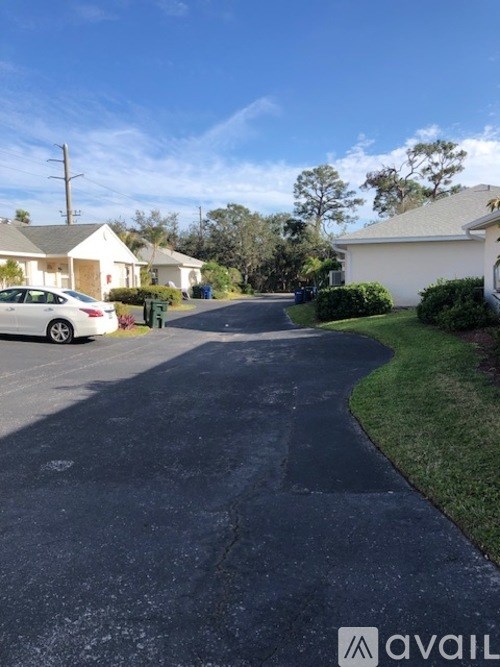 A residential street with houses on both sides and a car parked on the left.