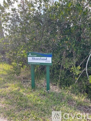 A green sign that says Shoreland Park stands in front of some bushes.