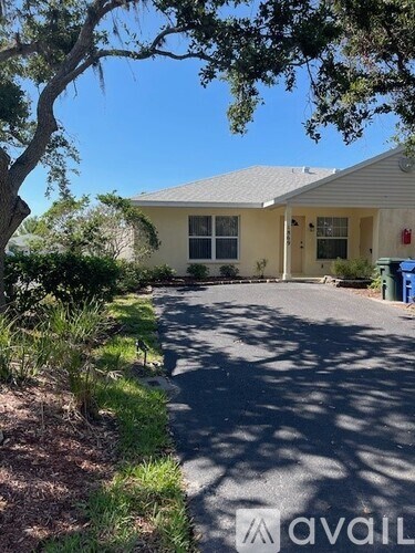 A house with a driveway and a tree in front.