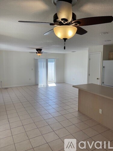 A spacious room with a ceiling fan and tiled flooring.