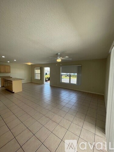A spacious room with tile flooring and a ceiling fan.