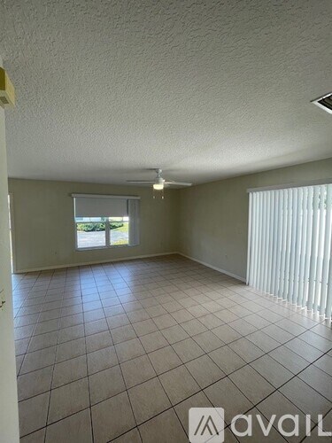 A room with tiled flooring and a window with blinds.