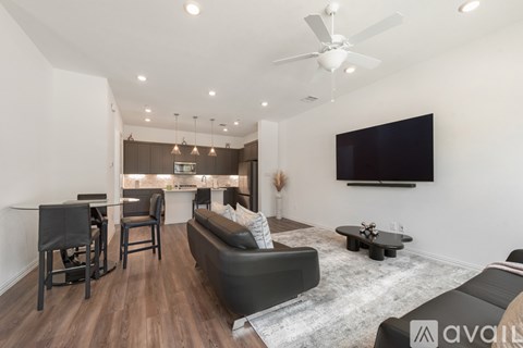 A living room with a grey couch and a television on the wall.