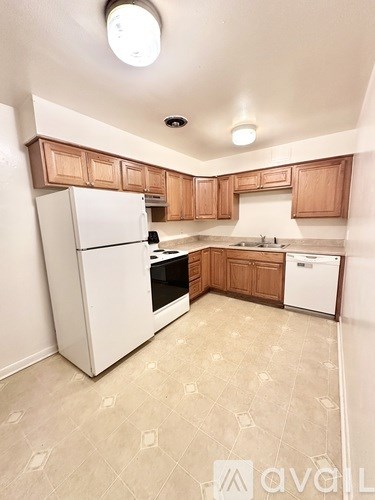 A kitchen with a white refrigerator and wooden cabinets.
