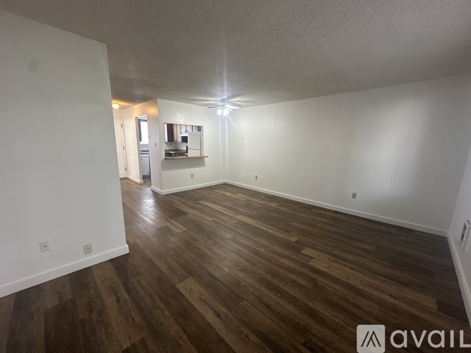 A spacious room with wooden flooring and white walls.