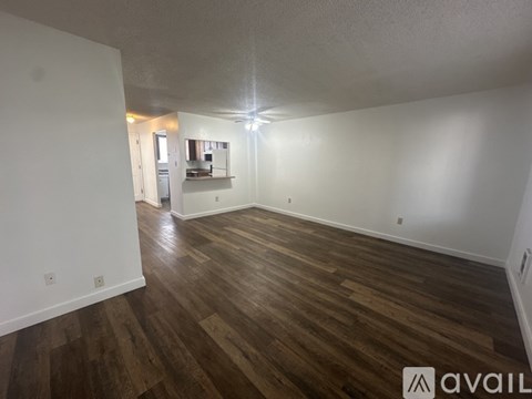 A spacious room with wooden flooring and white walls.