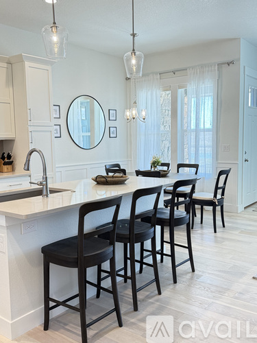 A kitchen with white cabinets and a white counter top with four black chairs.