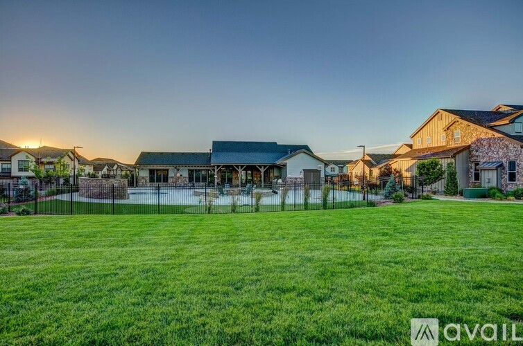 A sunset view of a residential area with houses and a pool.