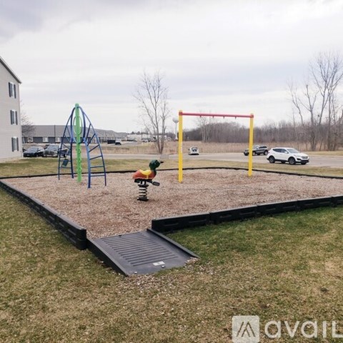 A playground with a slide, swings, and a seesaw.