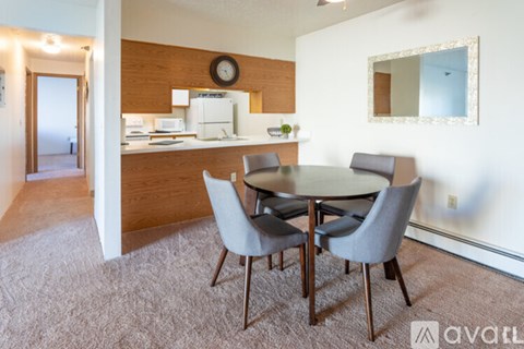 A dining room with a round table and grey chairs.