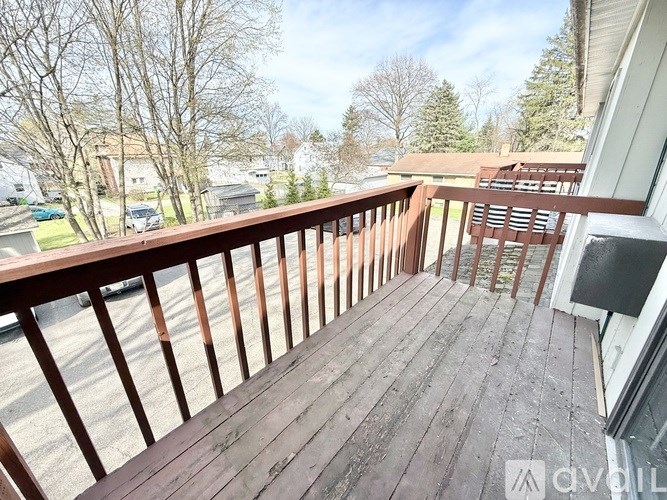 A wooden deck with a railing and a view of a residential area.