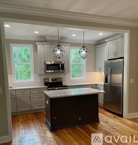 A kitchen with a large island in the middle and a refrigerator to the right.