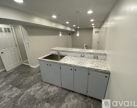 A kitchen island with a sink in a room with grey flooring and white walls.