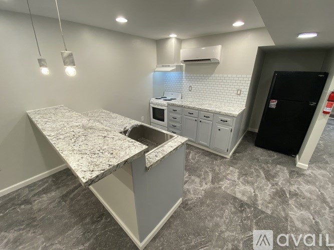 A kitchen with granite countertops and a black refrigerator.