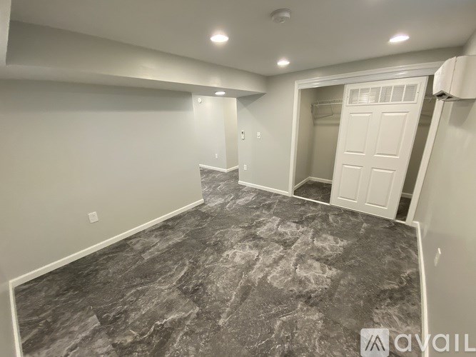 A spacious room with a marble floor and a doorway leading to another room.