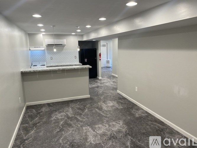 A spacious room with a kitchenette and grey marble flooring.