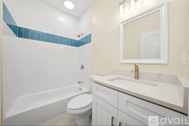 A bathroom with a white toilet, a white sink, and a white bathtub with blue tiles on the wall.