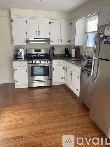 A kitchen with white cabinets and a wooden floor.