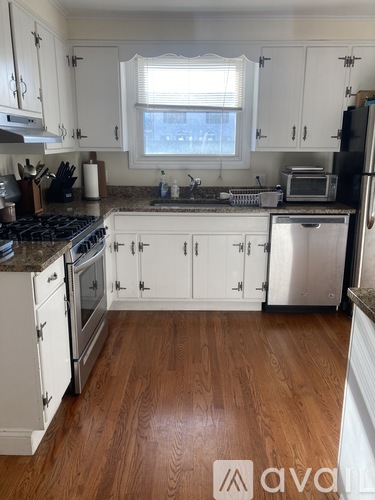 A kitchen with white cabinets and a wooden floor.