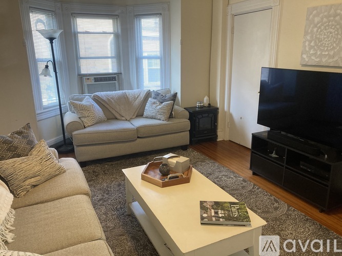 A living room with a grey couch, a white coffee table, and a black television.