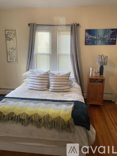 A bedroom with a bed, nightstand, and a painting on the wall.