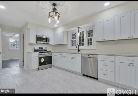 A bright kitchen with white cabinets and appliances.
