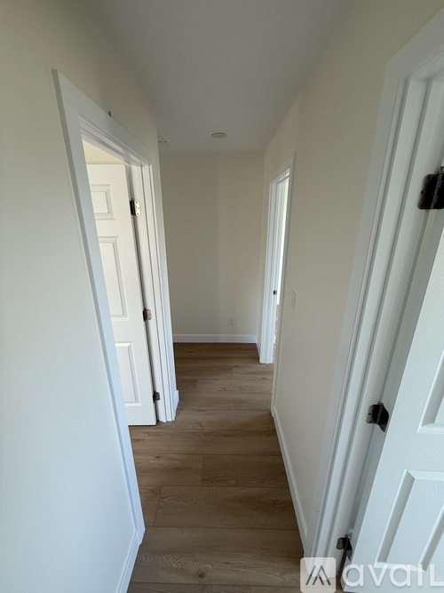 A hallway with white doors and wooden floors.