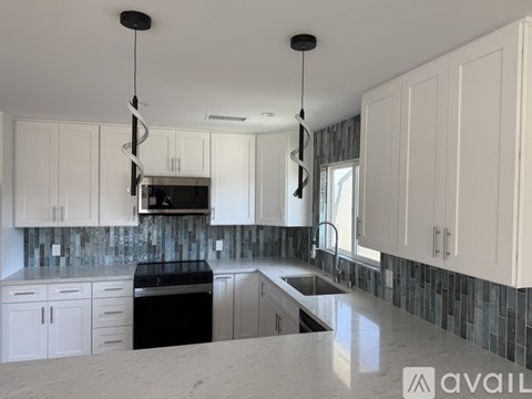 A kitchen with white cabinets and a black dishwasher.