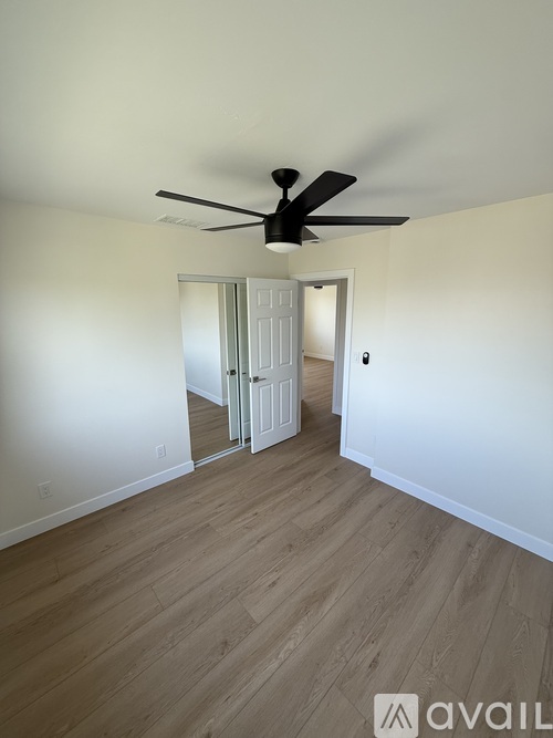 A room with a ceiling fan and wooden flooring.