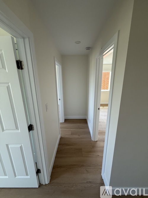 A hallway with a door on the left and a window on the right.