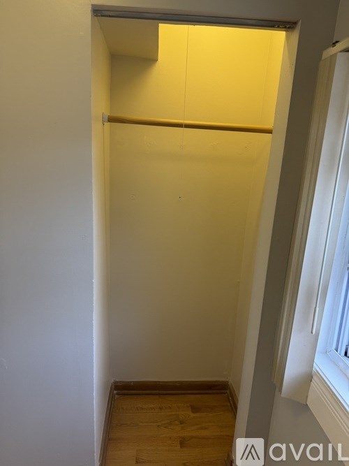 A small room with a window and wooden flooring.