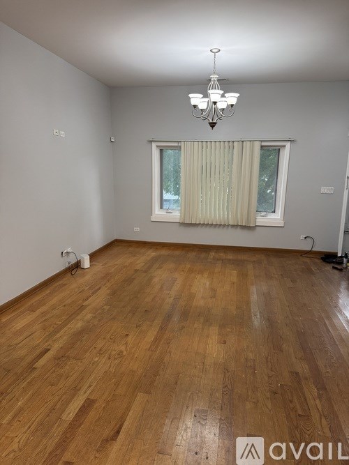 A room with wooden flooring and a chandelier.