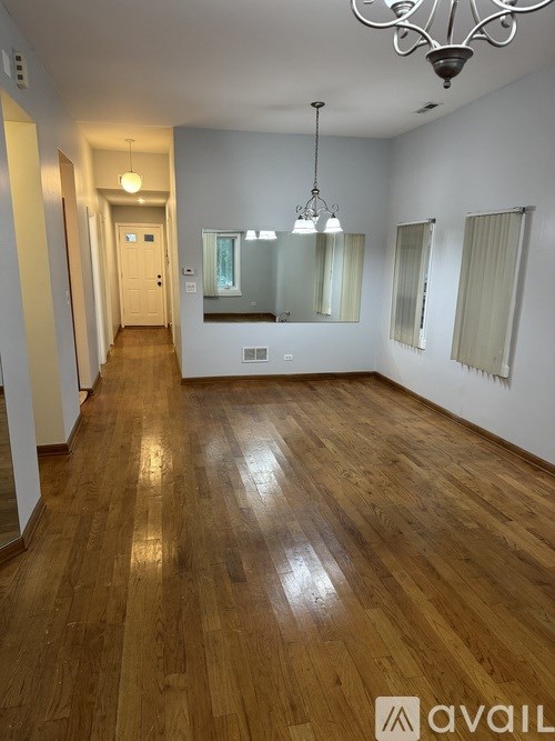A long hallway with wooden floors and a chandelier.