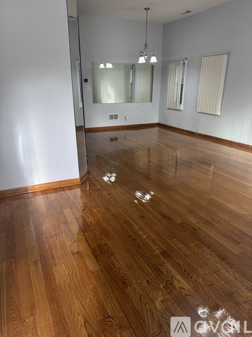 A room with wooden flooring and a large mirror on the wall.