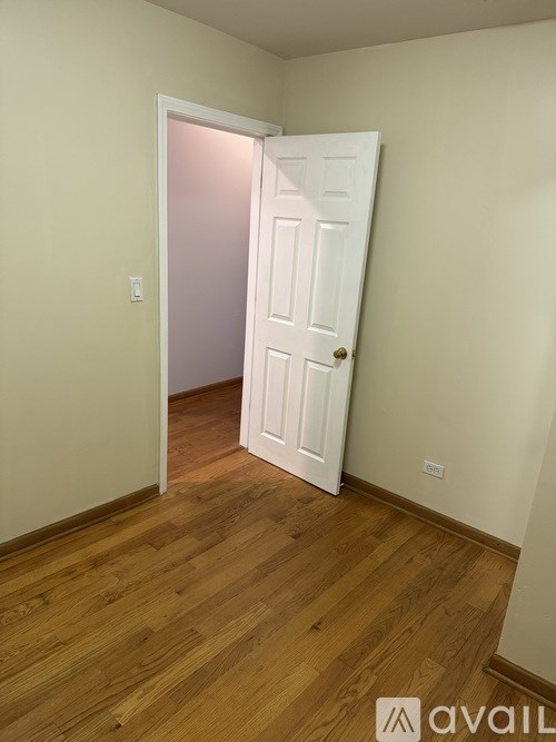A room with a white door and wooden floor.