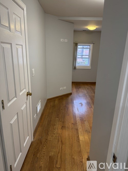 A hallway with a wooden floor and white walls.