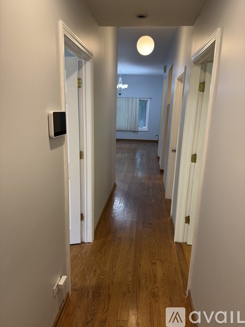 A hallway with a light on the ceiling and a door on the left.