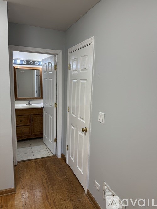 A white door is open to a bathroom with a mirror and a vanity.