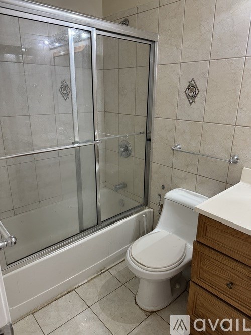 A bathroom with a toilet, a walk-in shower, and a wooden vanity.